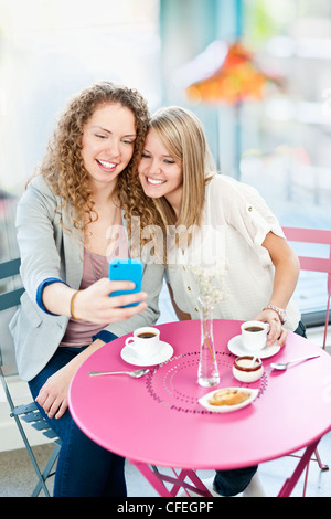 Deux smiling women looking at smart phone in cafe Banque D'Images