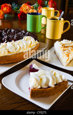 Pâtisserie néerlandaise différents ou flans limbourgeois avec tasses, mugs et fleurs prêt pour un parti - verticale Banque D'Images