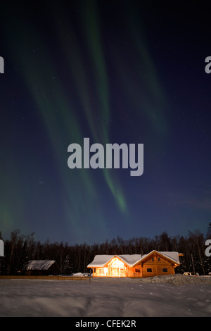 La faiblesse des aurores boréales sur log house en Alaska Banque D'Images