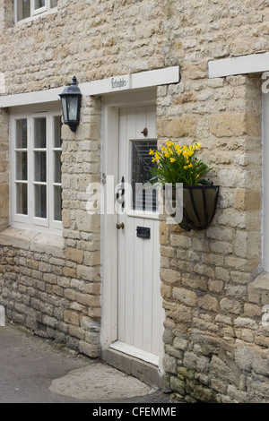 L'Angleterre est plus jolie petite ville médiévale à la passerelle Burford Cotswolds dans l'Oxfordshire cottage en pierre les jonquilles sur le mur Banque D'Images