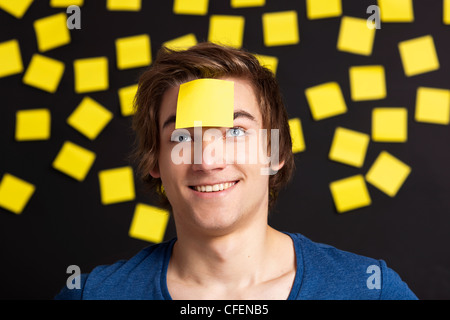 Happy student avec un rappel sur la tête, et avec plus de notes papier jaune à l'arrière-plan Banque D'Images