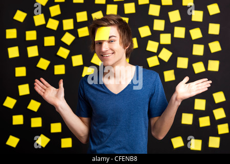 Happy student avec un rappel sur la tête, et avec plus de notes papier jaune à l'arrière-plan Banque D'Images