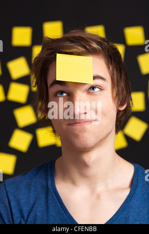 Happy student avec un rappel sur la tête, et avec plus de notes papier jaune à l'arrière-plan Banque D'Images