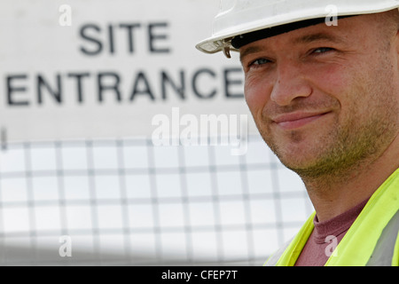 Un modèle est fait passer pour un ouvrier wearing hard-hat, hi-vis veste avec signe pour construction site Banque D'Images