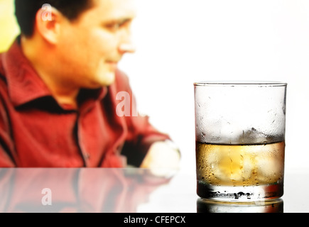 Verre de whisky avec de la glace et les hommes de flou artistique en arrière-plan Banque D'Images