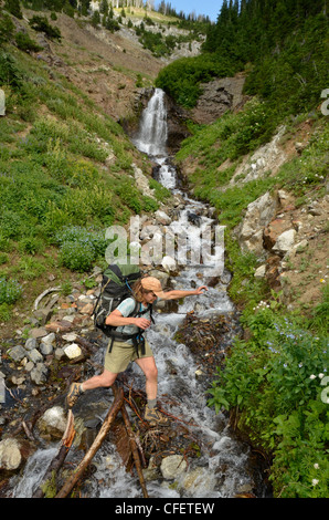 Backpacker traversant un ruisseau dans les montagnes de l'Oregon Wallowa. Banque D'Images