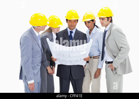 Les personnes portant des casques de sécurité regardant des plans de construction Banque D'Images