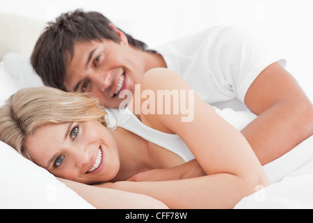 L'homme et la femme heureux au lit, l'homme par le bras enroulé autour de la femme Banque D'Images