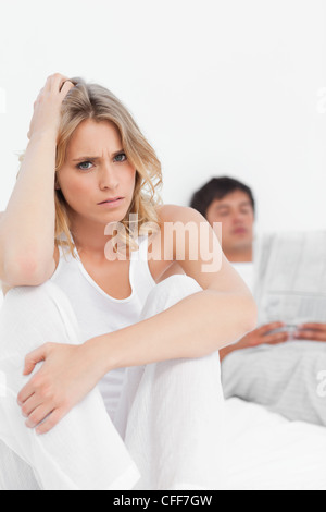Close up, à la femme concernée comme l'homme est assis en arrière et lit Banque D'Images