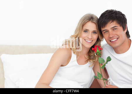 La femme et l'homme sourire en regarder droit devant avec une rose dans sa main Banque D'Images