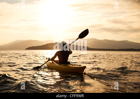 Une bonne femme athlétique kayak au coucher du soleil sur un lac dans l'Idaho. Banque D'Images