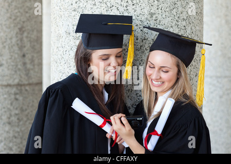 Les jeunes young smiling graduating in d'un appareil photo numérique Banque D'Images