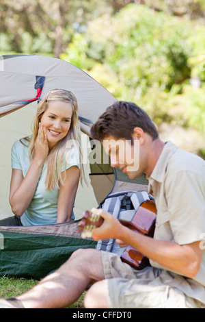 Une femme tombe amoureux encore plus avec son petit ami comme il joue de la guitare Banque D'Images