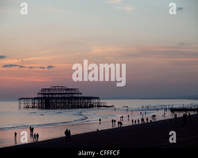 Marée basse lorsque le soleil se couche derrière la jetée Ouest à Brighton Banque D'Images