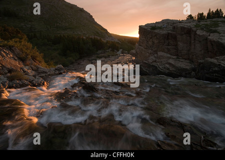 Lever du soleil sur une rivière qui coule du lac McDonald, dans le parc national des Glaciers dans les Montagnes Rocheuses. Banque D'Images