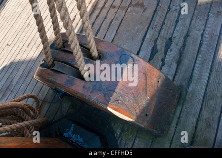 Vieux bois pully sur le pont d'un navire avec des cordes qui s'étend vers le haut vers le mât. Banque D'Images