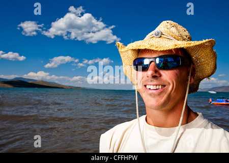 Un homme sourit dans un chapeau de paille qu'il représente un portrait sur les rives du lac de l'Ours, de l'Utah. Banque D'Images