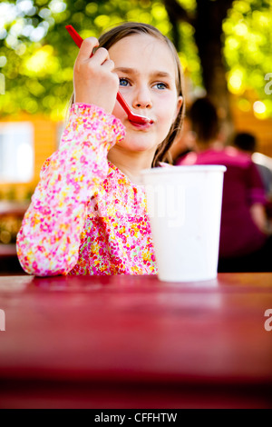 Une fillette de huit ans, mange la crème glacée tout en étant assis à la table de pique-nique, Garden City, Utah. Banque D'Images