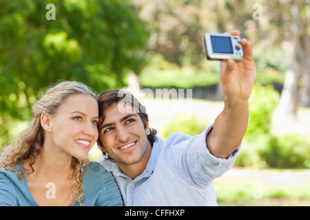 Couple dans le parc pour prendre des photos d'eux-mêmes Banque D'Images