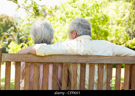 Homme assis sur un banc avec son bras autour de son ami Banque D'Images
