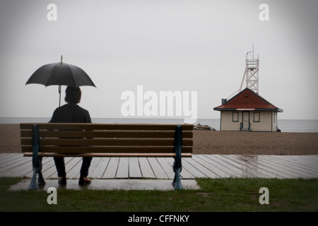 Homme assis sur un banc avec parasol, Woodbine Beach, Toronto, Ontario Banque D'Images