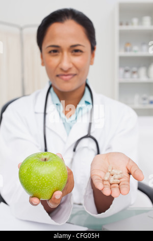 Médecin détendue tenant une pomme verte et des vitamines Banque D'Images