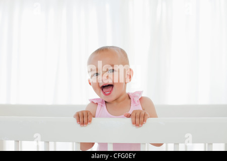 Beau Bébé debout dans son lit tout en criant Banque D'Images