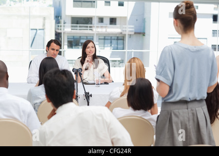 Femme parlant à deux personnes assises derrière une table Banque D'Images