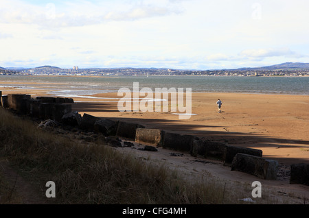 Personne courant sur la plage de point de Tentsmuir avec l'estuaire de la Tay et Dundee à travers l'eau Banque D'Images