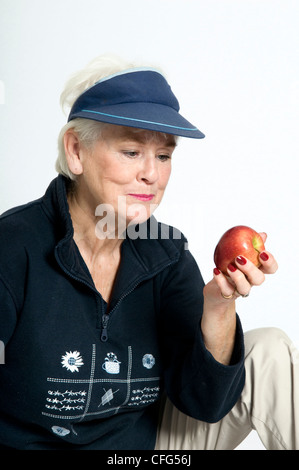 Senior lady à propos de manger pomme rouge prises sur un fond blanc. Banque D'Images