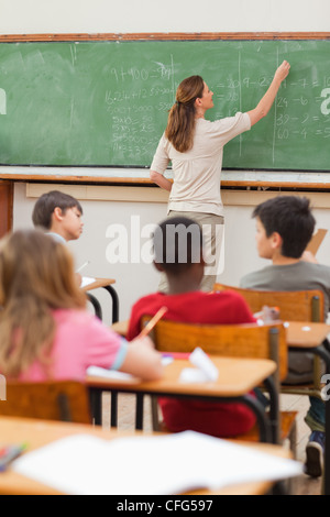 Problèmes de maths Teacher writing on blackboard Banque D'Images