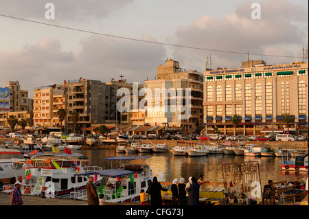 Tartous. La Syrie. La fin de l'après-midi soleil donne lueur chaude pour le port des bateaux de pêche et les bâtiments de la zone côtière au bord de l'eau Banque D'Images