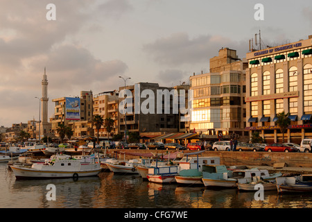 Tartous. La Syrie. La fin de l'après-midi soleil donne lueur chaude pour le port des bateaux de pêche et les bâtiments de la zone côtière au bord de l'eau Banque D'Images