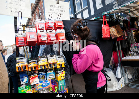 Girl examine les marchandises sur une échoppe de marché tout en parlant sur un téléphone mobile Banque D'Images