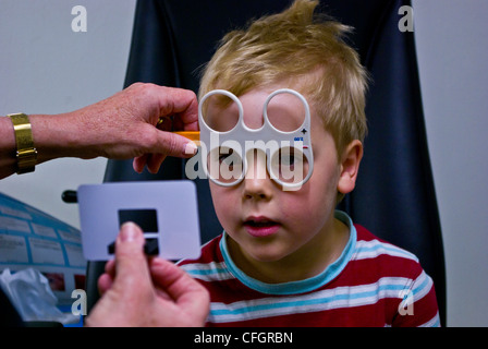 Un optométriste d'enfants donne un petit garçon de son premier examen de la vue. Banque D'Images