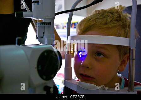 Un optométriste d'enfants donne un petit garçon de son premier examen de la vue. Banque D'Images