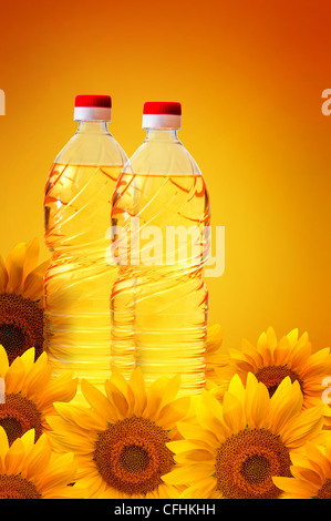 L'huile de tournesol dans les bouteilles en plastique sur un fond chaud et ensoleillé, le tournesol éparpillés. Banque D'Images