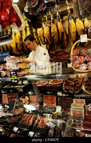 Homme travaillant dans un charcuteria / porc / boucherie charcuterie dans le marché Boqueria / Mercat de la Boqueria à Barcelone, Espagne Banque D'Images