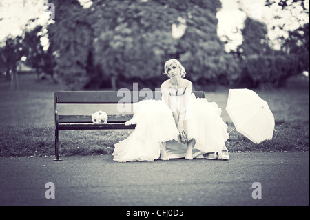 Ennuyer bride sitting on bench en attente de mari Banque D'Images