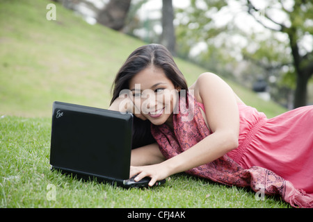 Young woman lying on grass et à l'aide d'un ordinateur portable Banque D'Images