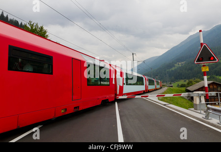 Train Glacier express route traverse un passage à niveau fermé avec porte, Suisse Banque D'Images