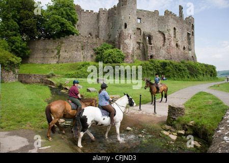 Les cavaliers et poney à travers un ruisseau à Laugharne, Camarthenshire, au Pays de Galles Banque D'Images