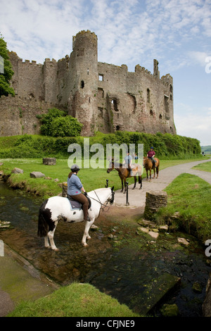Les cavaliers et poney à travers un ruisseau à Laugharne, Camarthenshire, au Pays de Galles Banque D'Images