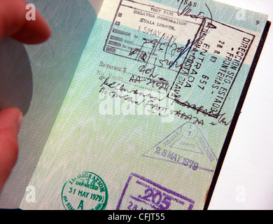 Main tenant ouvrir un ancien passeport britannique de style à une page avec l'entrée et la sortie du pays de l'immigration stamps Banque D'Images