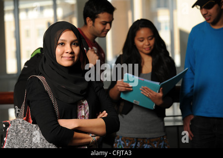 Jeune étudiant arabe holding books in College Campus avec divers groupes dans l'arrière-plan Banque D'Images