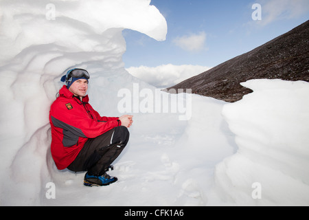 Les alpinistes ayant trouvé refuge dans un ancien trou à neige dans la neige s'est incliné contre un esker à Coire une Sneachda dans le Cairngorms, Banque D'Images