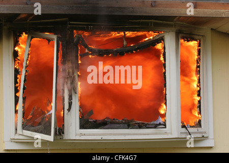 Fenêtre en baie d'une maison en feu avec des flammes à l'intérieur de la structure de la maison Banque D'Images