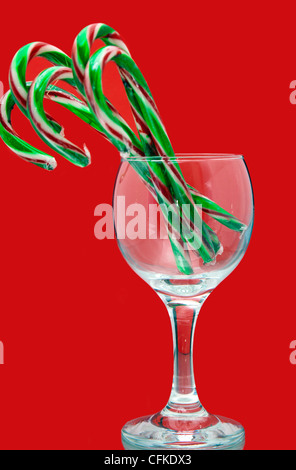 Ambiance festive Christmas candy canes dans un verre à vin sur fond rouge Banque D'Images