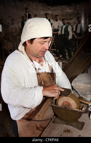 Abbot'S Salford, Warwickshire, Mary Arden's Farm, l'homme sur l'axe d'affûtage pierre à eau Banque D'Images