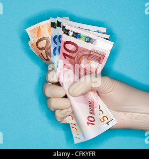 Main dans les gants chirurgicaux holding banknotes Banque D'Images